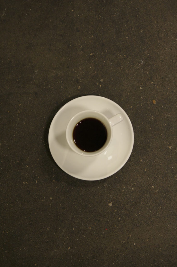 Cup of coffee with tray on floor, shot from above.